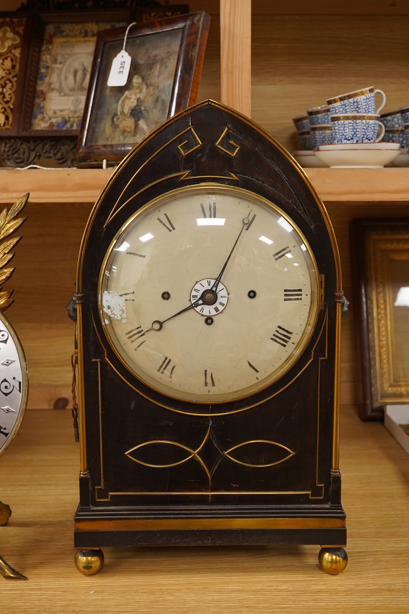 A Regency ebonised and brass inlaid lancet-shape bracket clock, with key and a painted pottery strut timepiece, largest 55cm high (2)